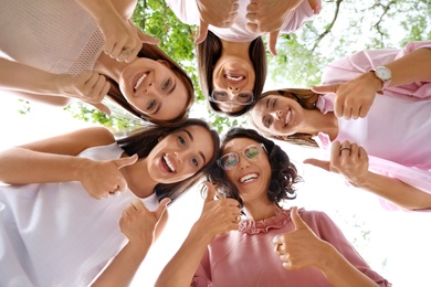 Photo of Happy women showing thumbs up outdoors, bottom view. Girl power concept
