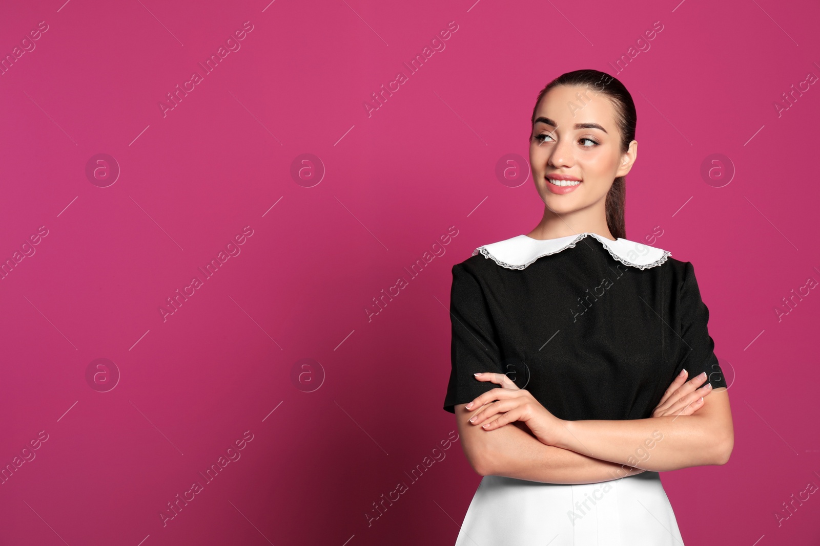 Photo of Portrait of young chambermaid in tidy uniform on color background