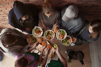 Poor people with plates of food indoors, view from above