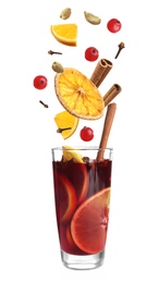 Image of Cut orange, cranberries and different spices falling into glass of mulled wine on white background 