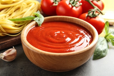 Bowl of tasty tomato sauce served on table, closeup