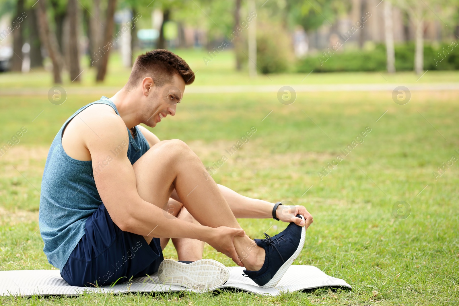 Photo of Male athlete suffering from foot pain during training outdoors