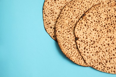 Photo of Tasty matzos on light blue background, flat lay with space for text. Passover (Pesach) celebration