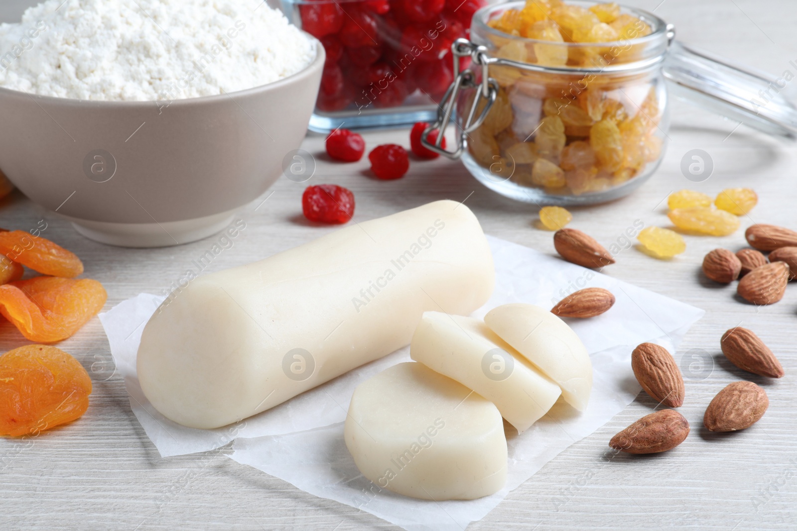 Photo of Marzipan and other ingredients for homemade Stollen on white wooden table. Baking traditional German Christmas bread