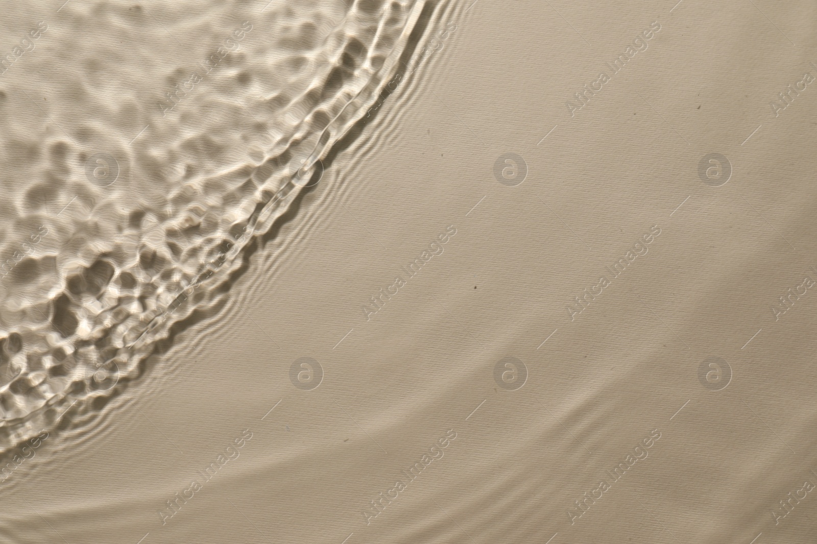 Photo of Rippled surface of clear water on beige background, top view