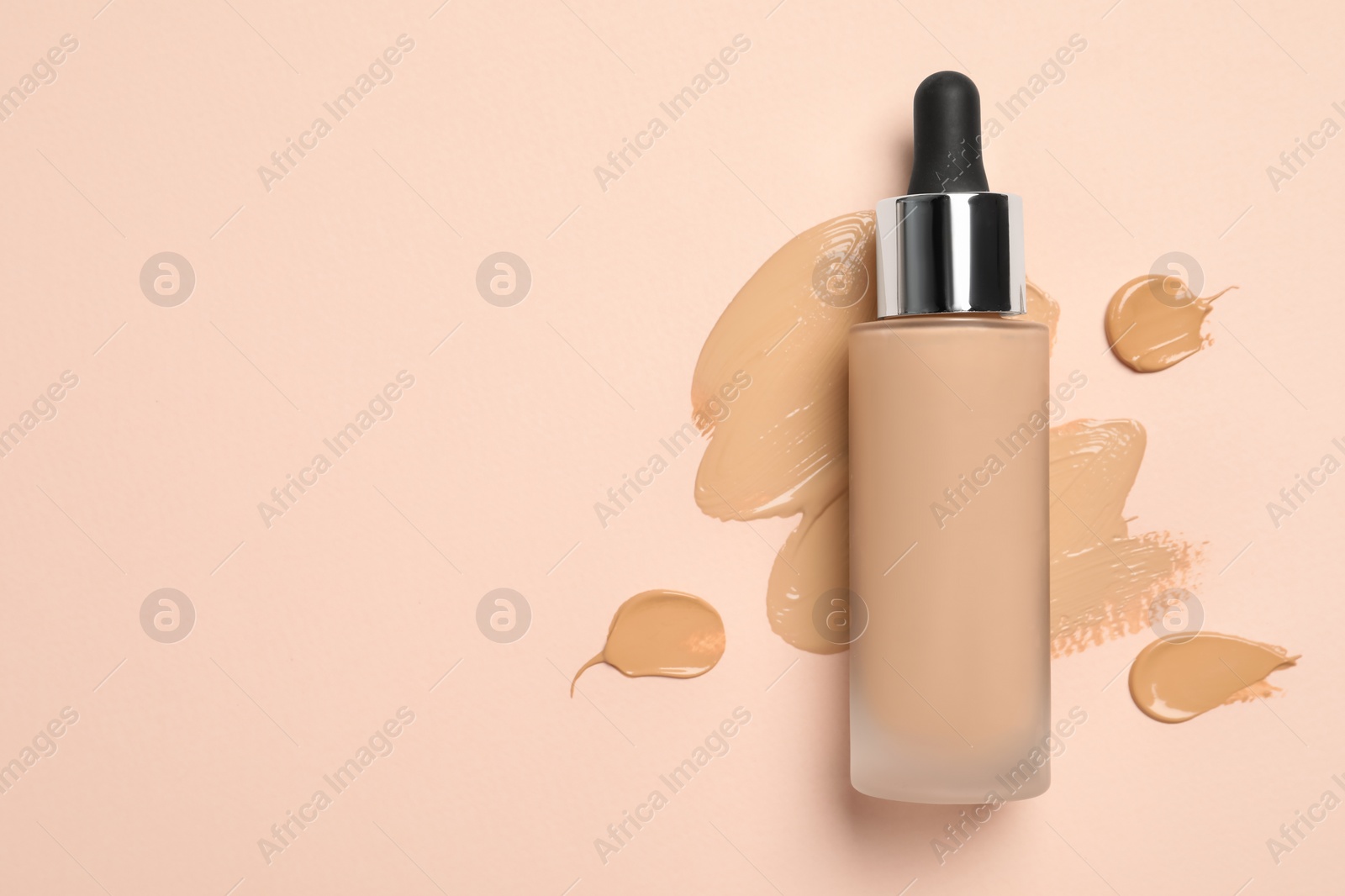 Photo of Liquid foundation and swatches on beige background, top view. Space for text