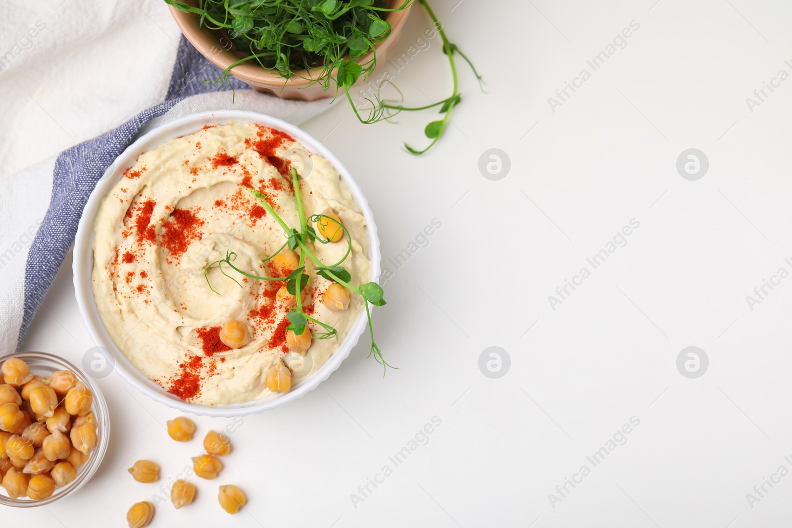 Photo of Delicious hummus with chickpeas and paprika served on white table, flat lay. Space for text