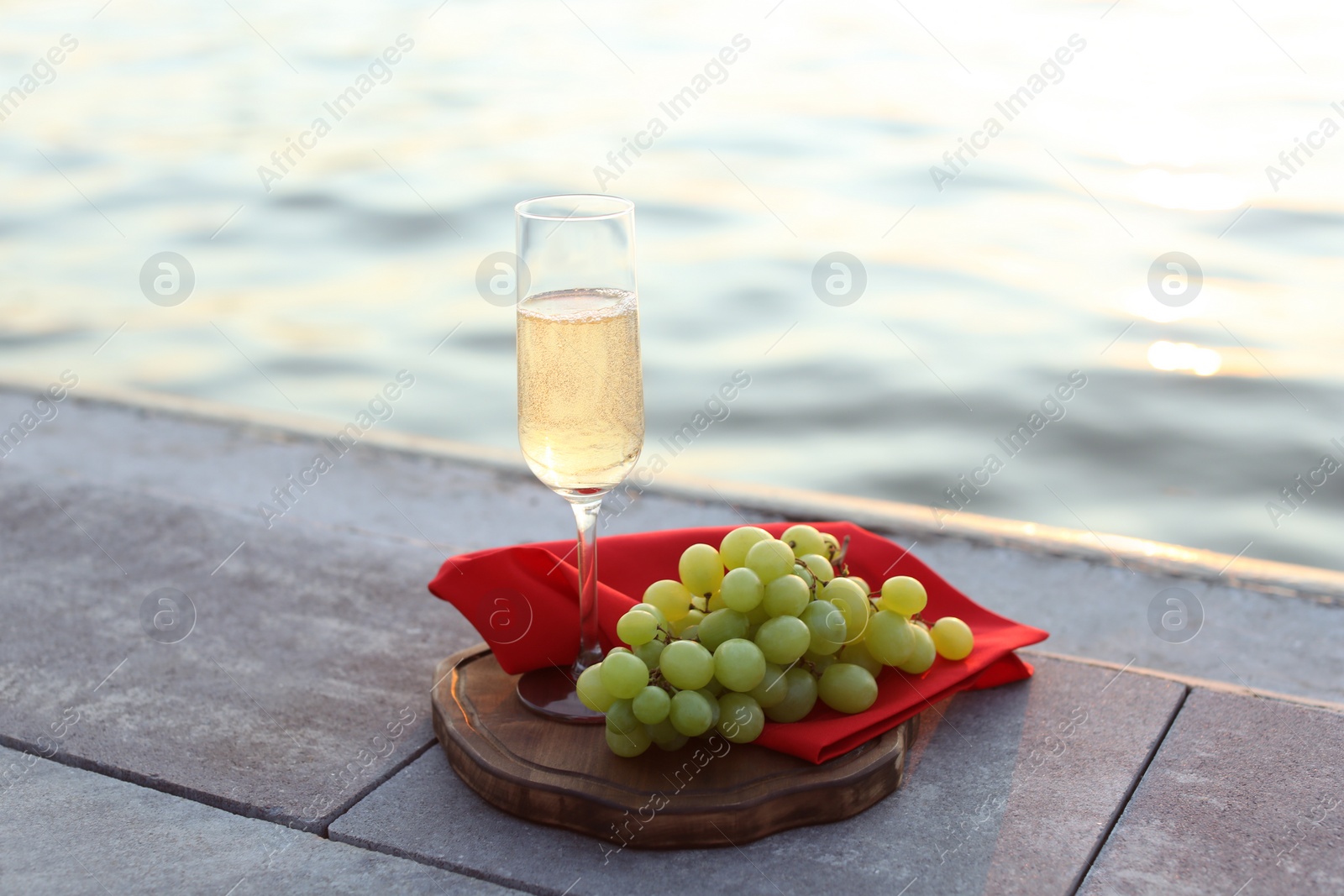 Photo of Glass of champagne and and fresh grapes served near river