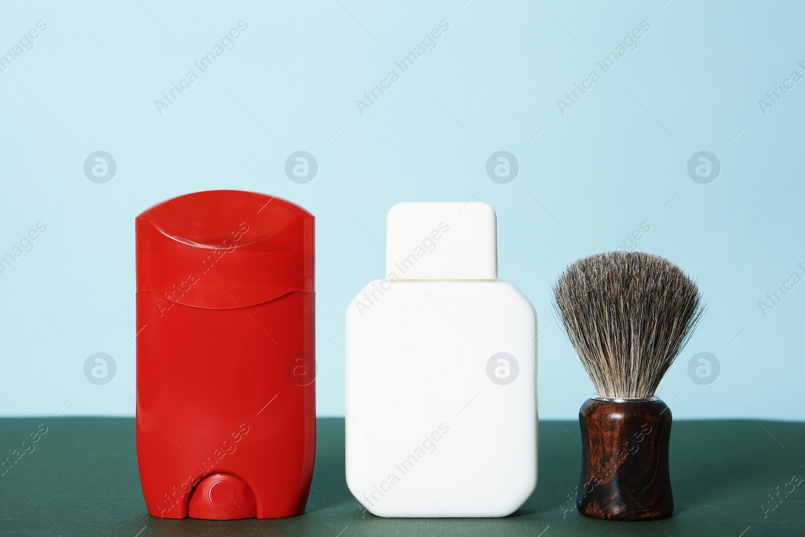 Photo of Shaving brush, lotion and deodorant for men on table against color background