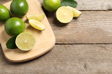 Whole and cut fresh limes on wooden table. Space for text