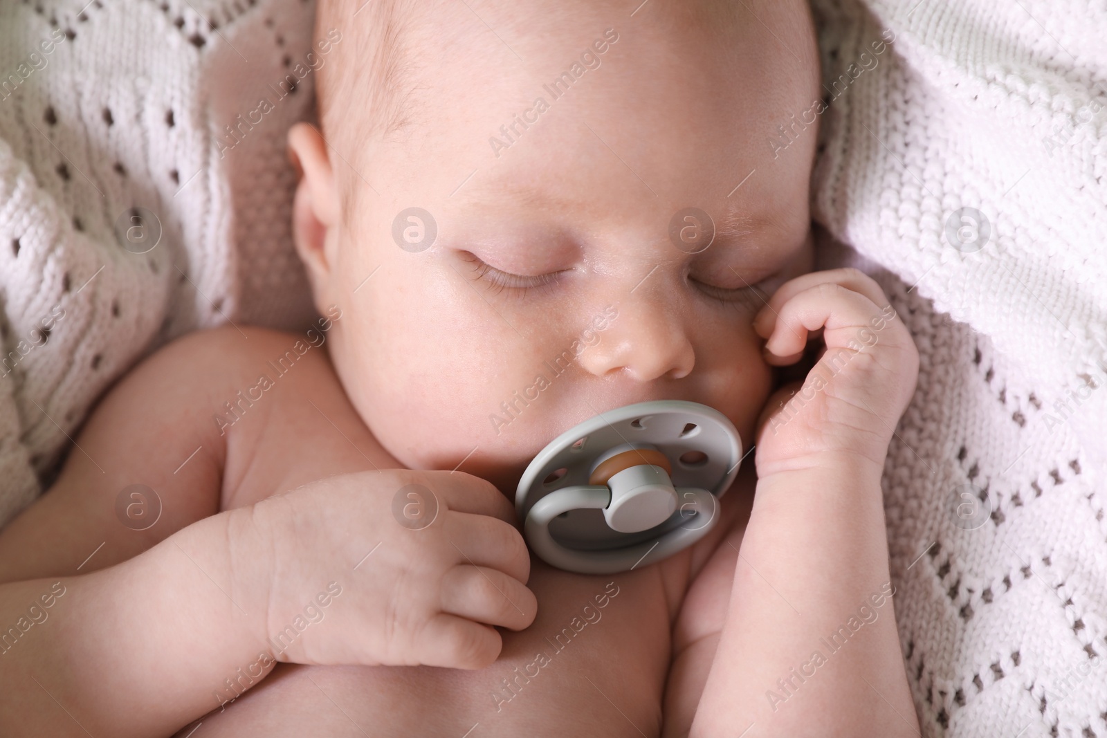 Photo of Cute newborn baby with pacifier sleeping on white blanket, closeup