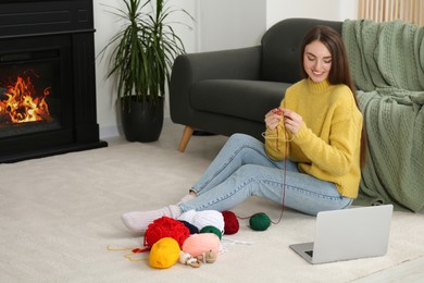 Photo of Young woman learning to knit with online course at home, space for text. Handicraft hobby