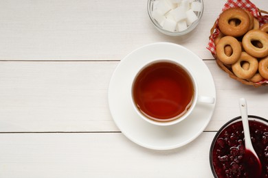 Photo of Flat lay composition with delicious ring shaped Sushki (dry bagels) and cup of tea on white wooden table, space for text