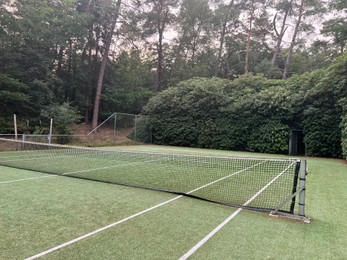 Tennis court with green grass and net outdoors