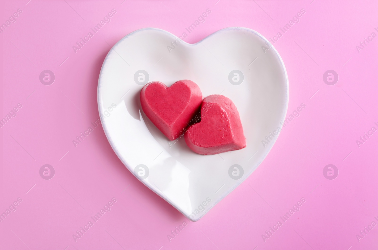 Photo of Plate with heart shaped berry ice cubes on color background, top view