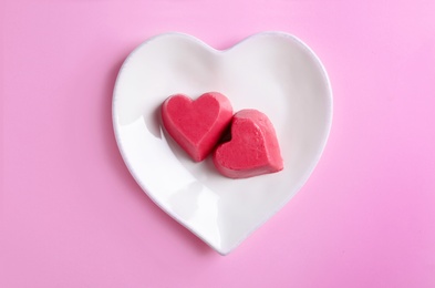 Plate with heart shaped berry ice cubes on color background, top view