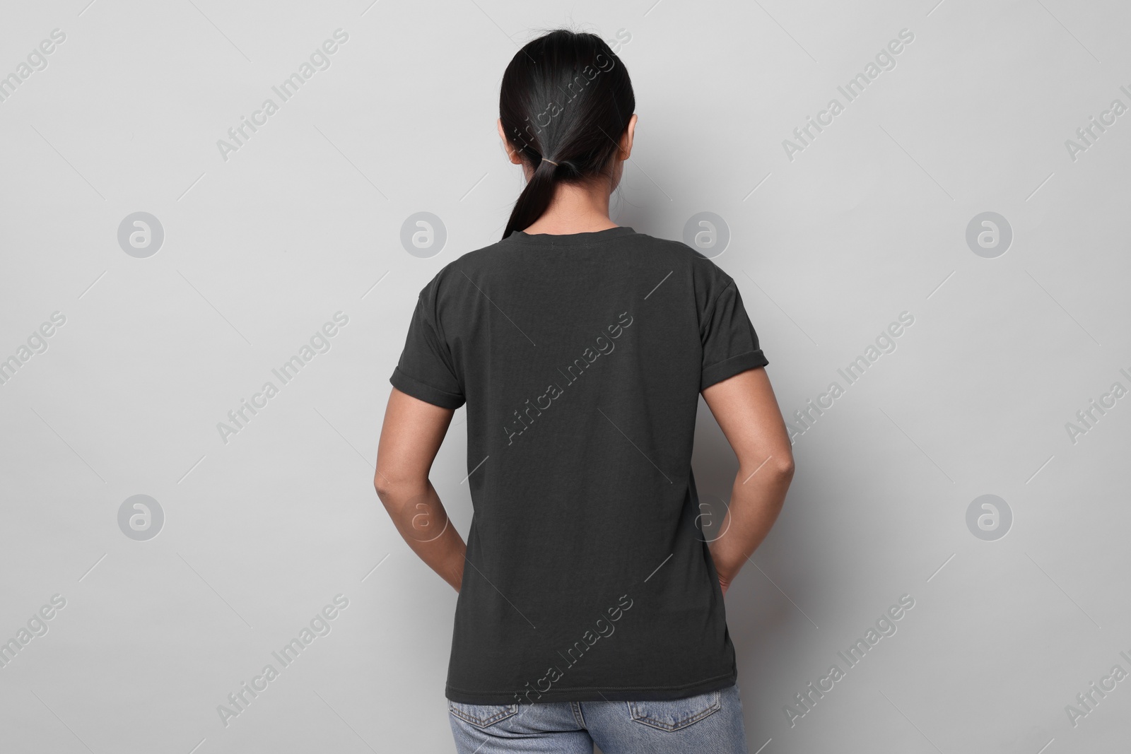 Photo of Woman wearing black t-shirt on light grey background, back view