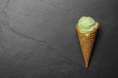 Photo of Delicious pistachio ice cream on dark table, top view. Space for text