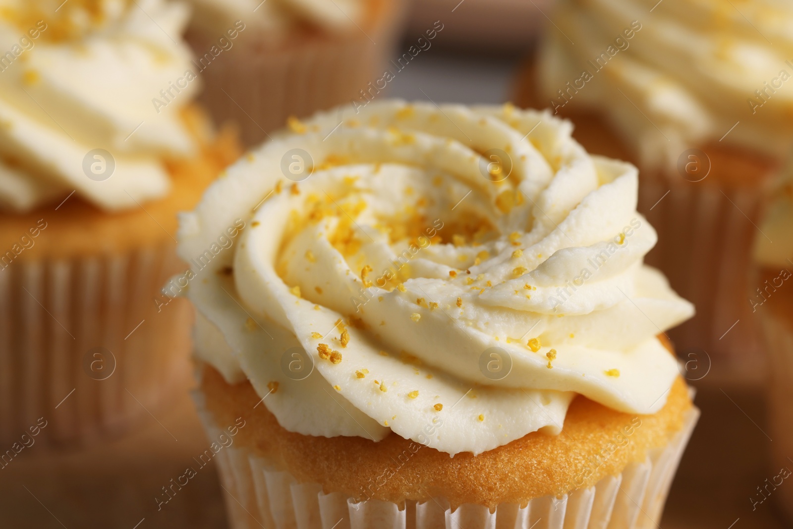 Photo of Delicious cupcakes with white cream and lemon zest, closeup