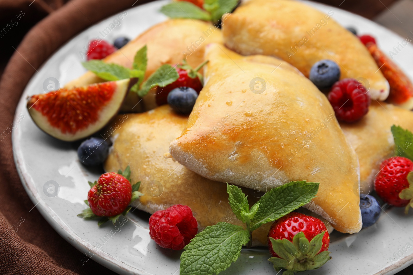 Photo of Delicious samosas with fig and berries on table, closeup