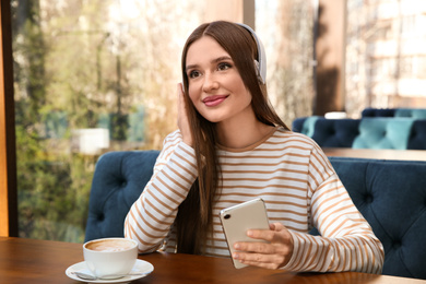 Woman listening to audiobook at table in cafe