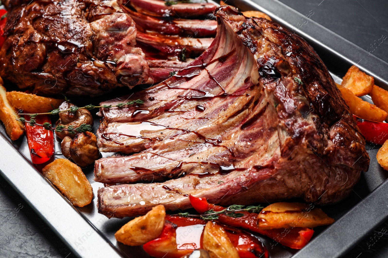 Photo of Delicious roasted ribs with garnish on table, closeup