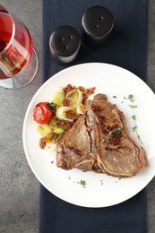 Photo of Delicious fried beef meat and vegetables served on grey table, top view