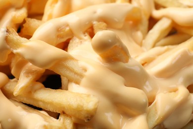 Delicious french fries with cheese sauce as background, closeup