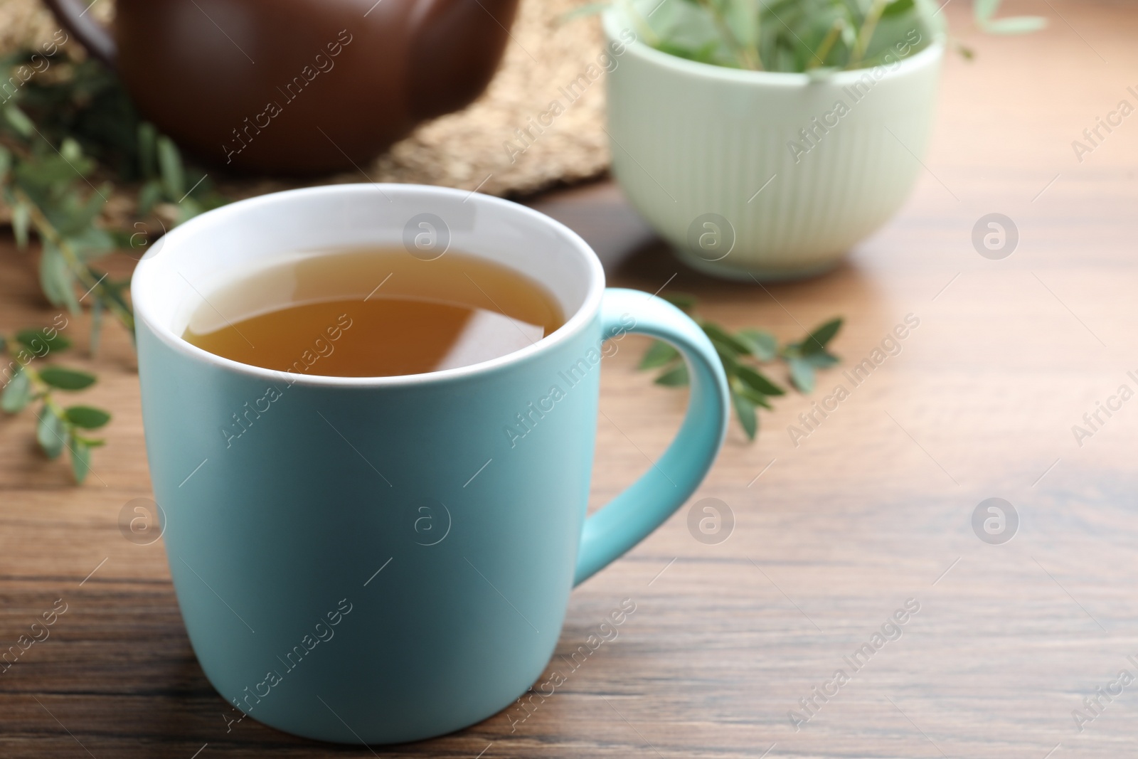 Photo of Cup of aromatic eucalyptus tea on wooden table, closeup. Space for text