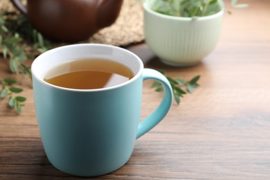 Photo of Cup of aromatic eucalyptus tea on wooden table, closeup. Space for text