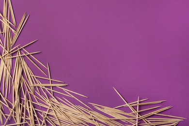 Photo of Wooden toothpicks on purple background, flat lay. Space for text