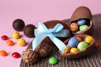 Tasty chocolate eggs and candies on pink background