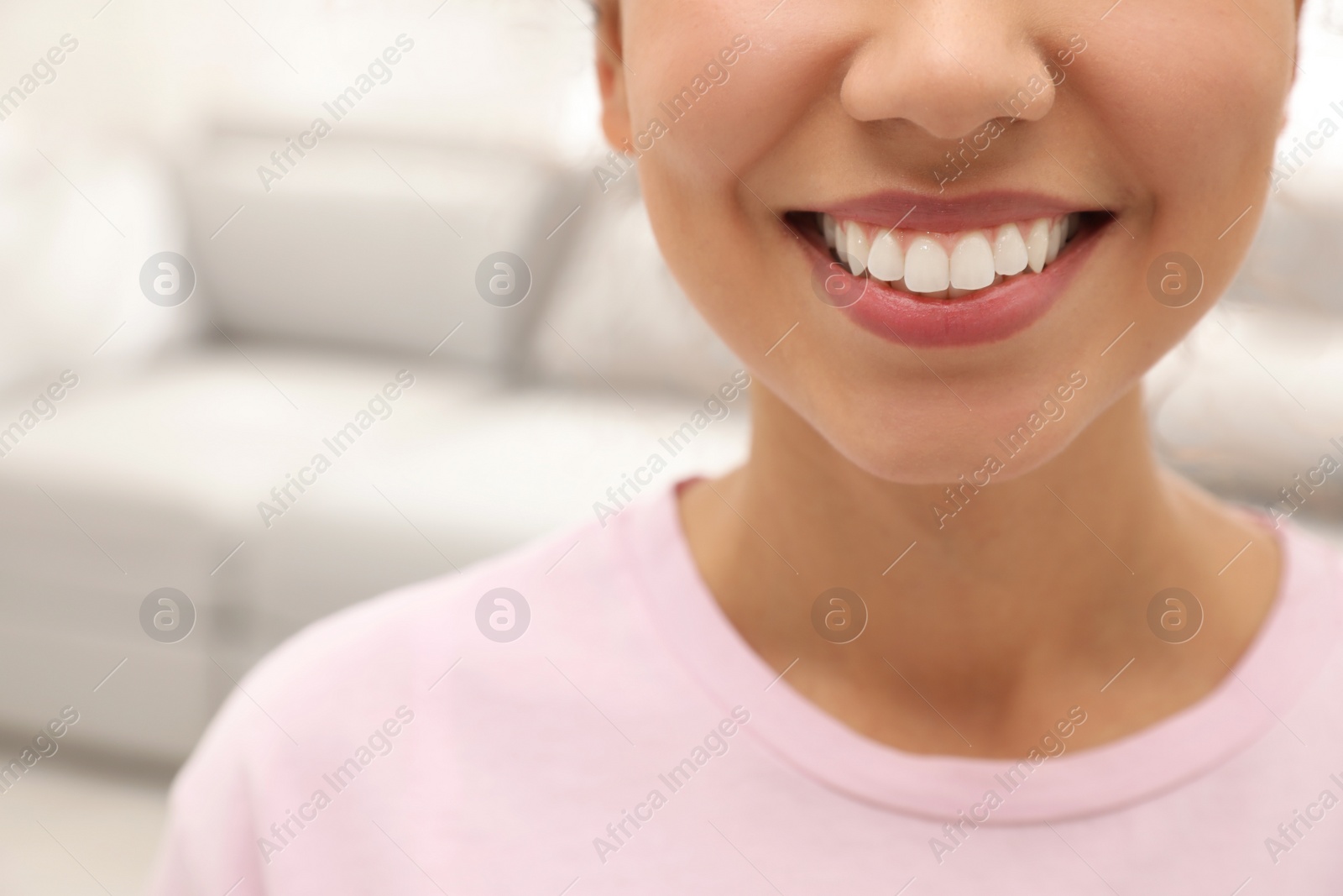 Photo of Young woman with healthy teeth on blurred background, closeup. Space for text