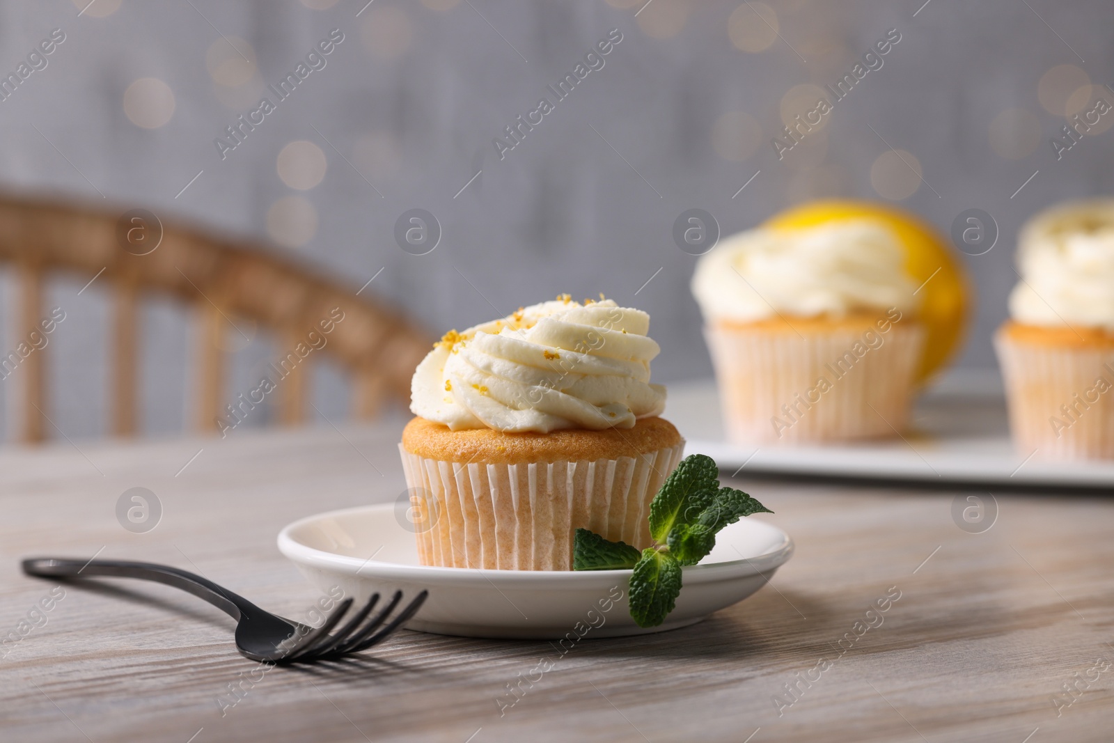 Photo of Delicious lemon cupcake with white cream served on wooden table