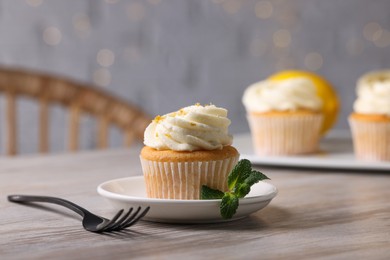 Photo of Delicious lemon cupcake with white cream served on wooden table