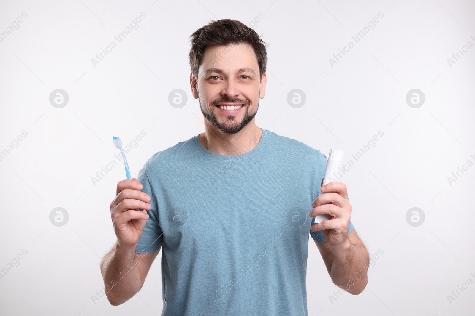 Photo of Happy man holding plastic toothbrush on white background. Mouth hygiene