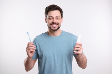 Photo of Happy man holding plastic toothbrush on white background. Mouth hygiene
