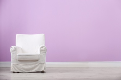 Stylish comfortable armchair near color wall