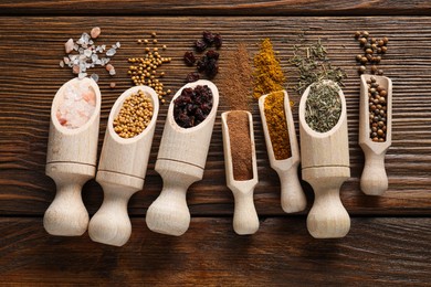 Scoops with different spices on wooden table, flat lay
