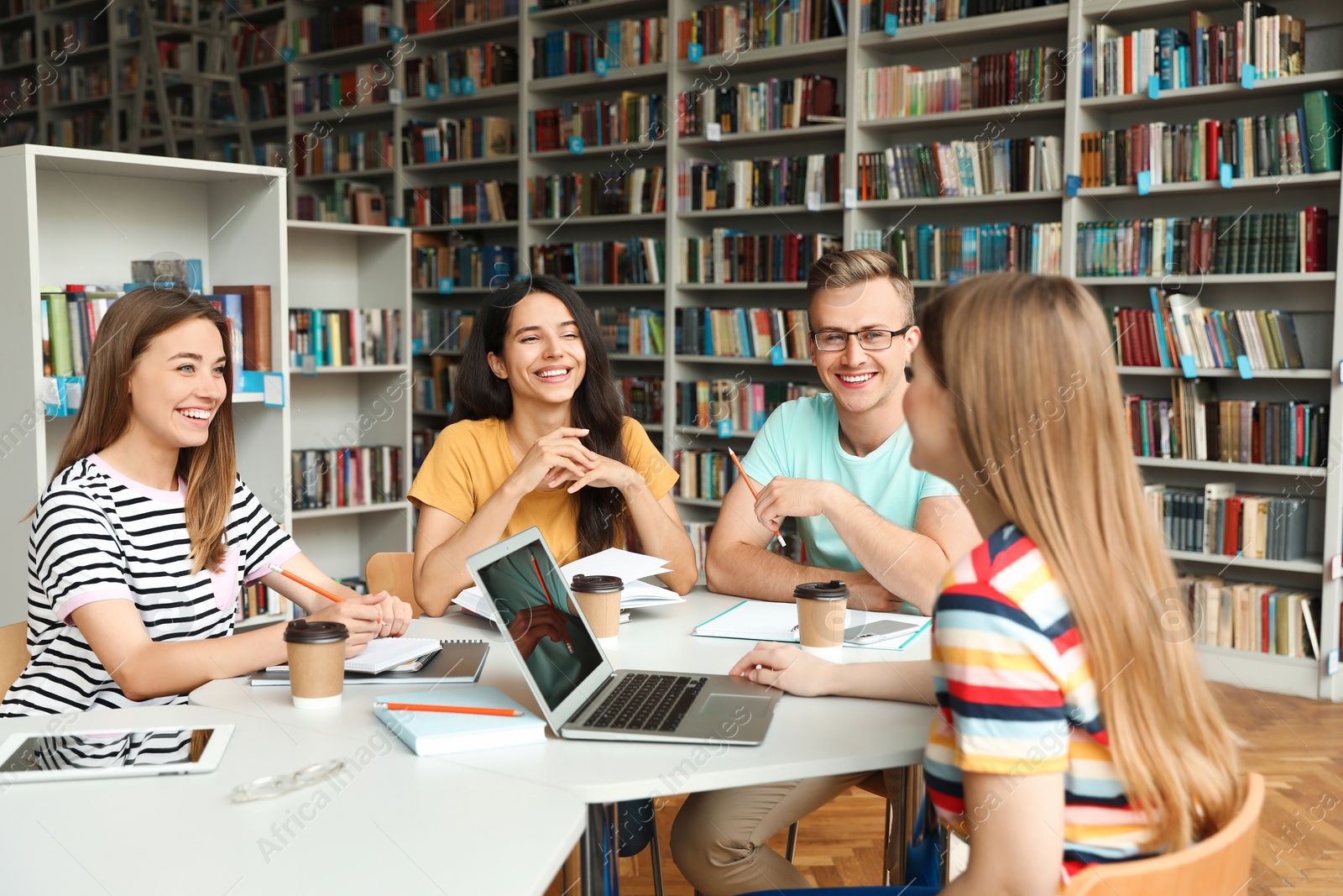 Photo of Young people discussing group project at table in library