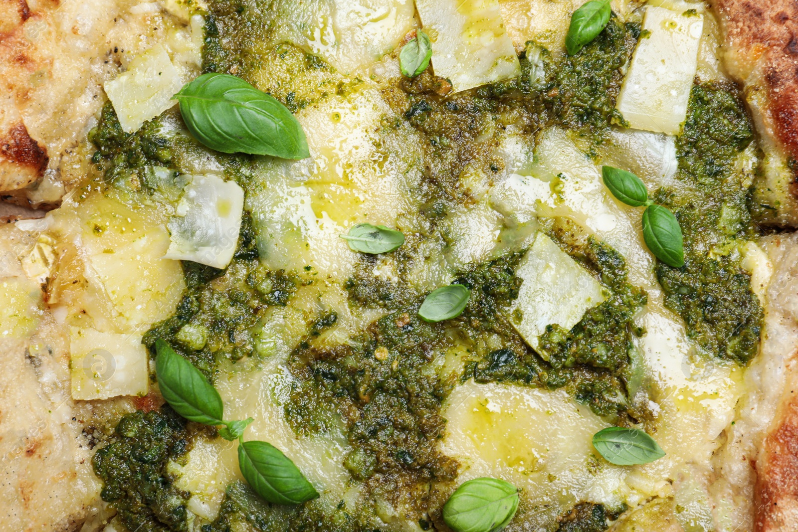 Photo of Delicious pizza with pesto, cheese and basil as background, top view