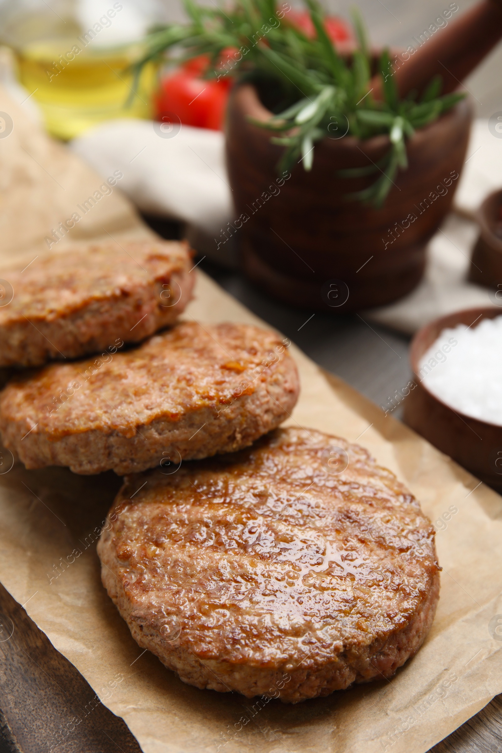 Photo of Serving board with tasty grilled hamburger patties on wooden table, closeup