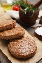 Photo of Serving board with tasty grilled hamburger patties on wooden table, closeup