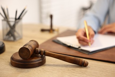 Photo of Notary with clipboard writing notes at workplace in office, focus on mallet