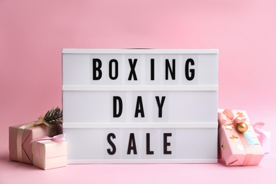 Photo of Lightbox with phrase BOXING DAY SALE and Christmas decorations on light pink background