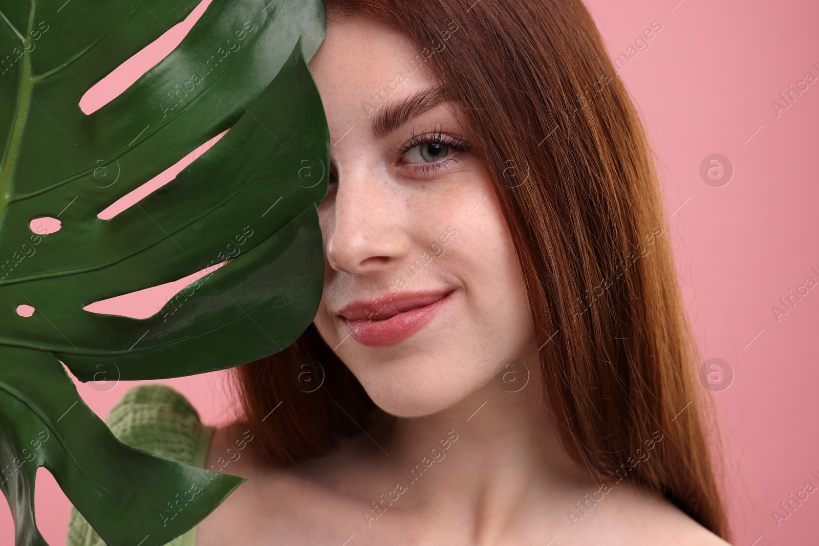 Photo of Portrait of beautiful woman with freckles and monstera leaf on pink background, closeup