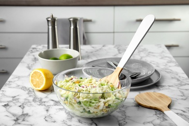 Bowl with fresh cabbage salad on marble table in kitchen