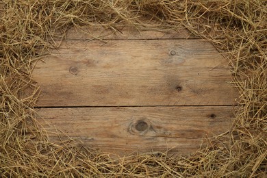 Frame made of dried hay on wooden background, top view. Space for text