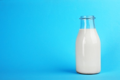 Photo of Glass bottle with fresh milk on color background. Space for text