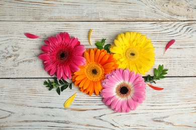 Flat lay composition with beautiful bright gerbera flowers on wooden background